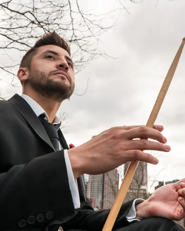 Nicko Guerrero with a drumstick against the Boston sky